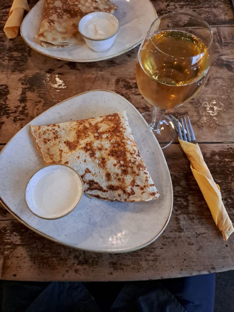 Crêpe salata del Pub Kompressor a Tallinn servita con un calice di vino bianco