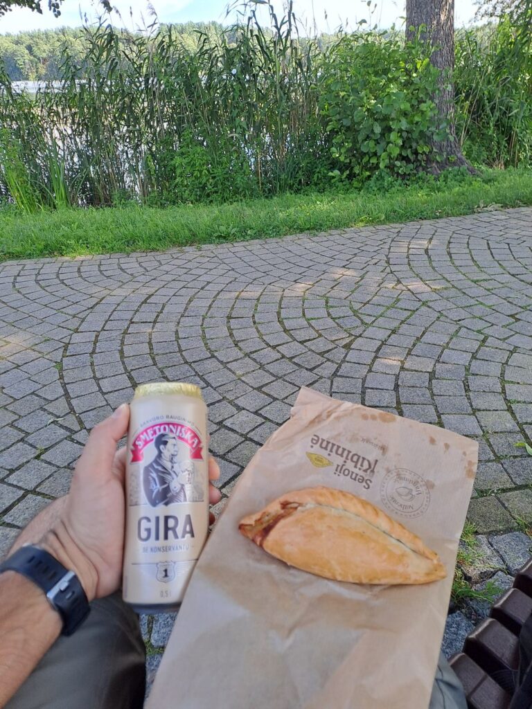 Un kibinas nel sacchetto di carta e una lattina di gira davanti al lago di Trakai